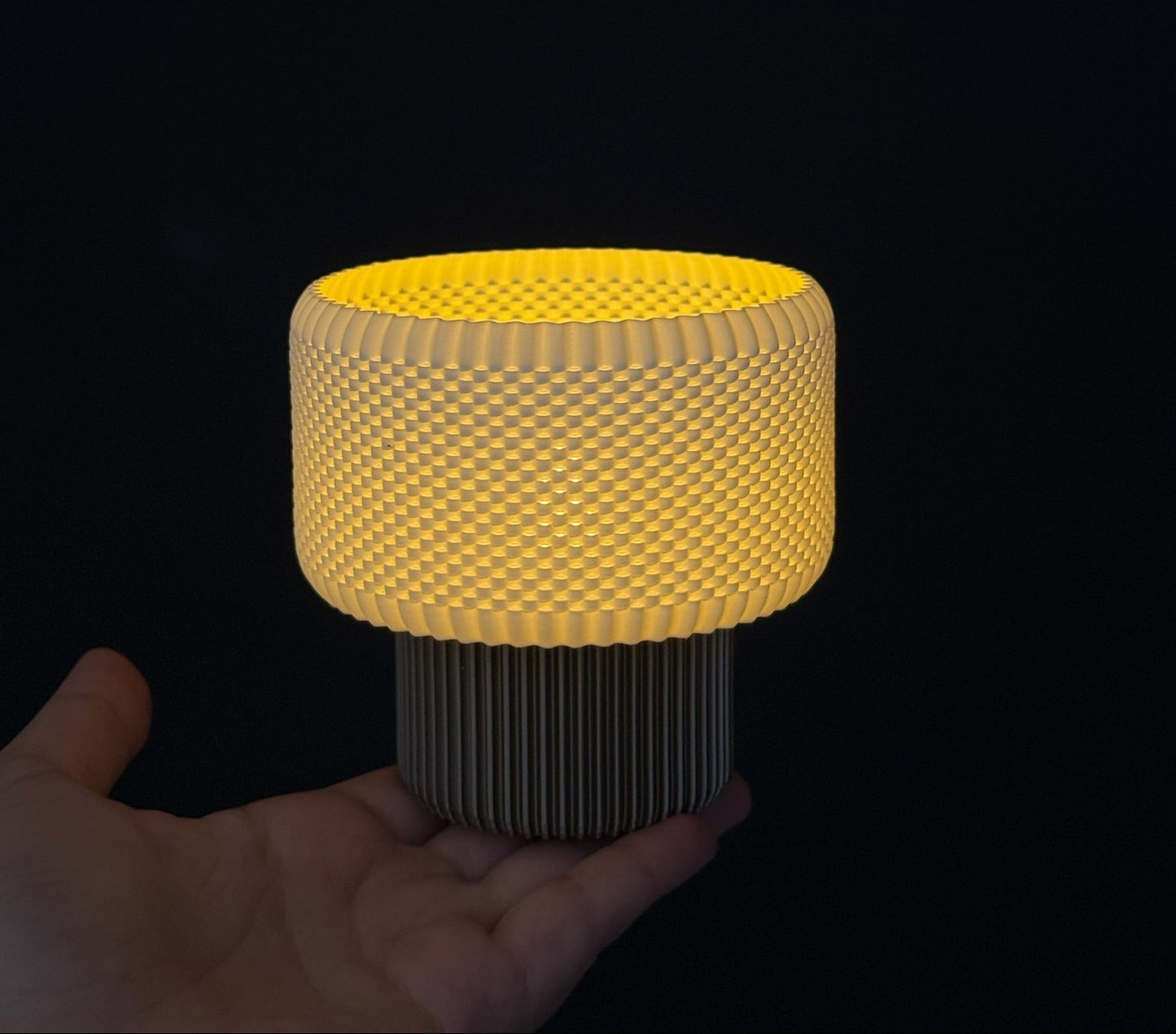 Yellow cylindrical light held in a hand against a black background