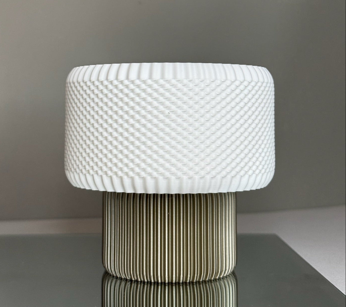 White textured table lamp on a dark surface with a neutral background