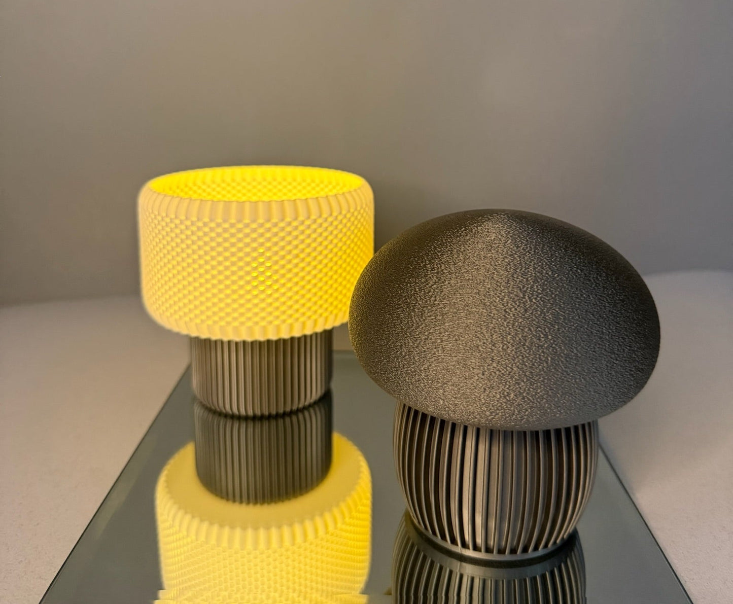 Two unique table lamps with textured designs on a reflective surface.